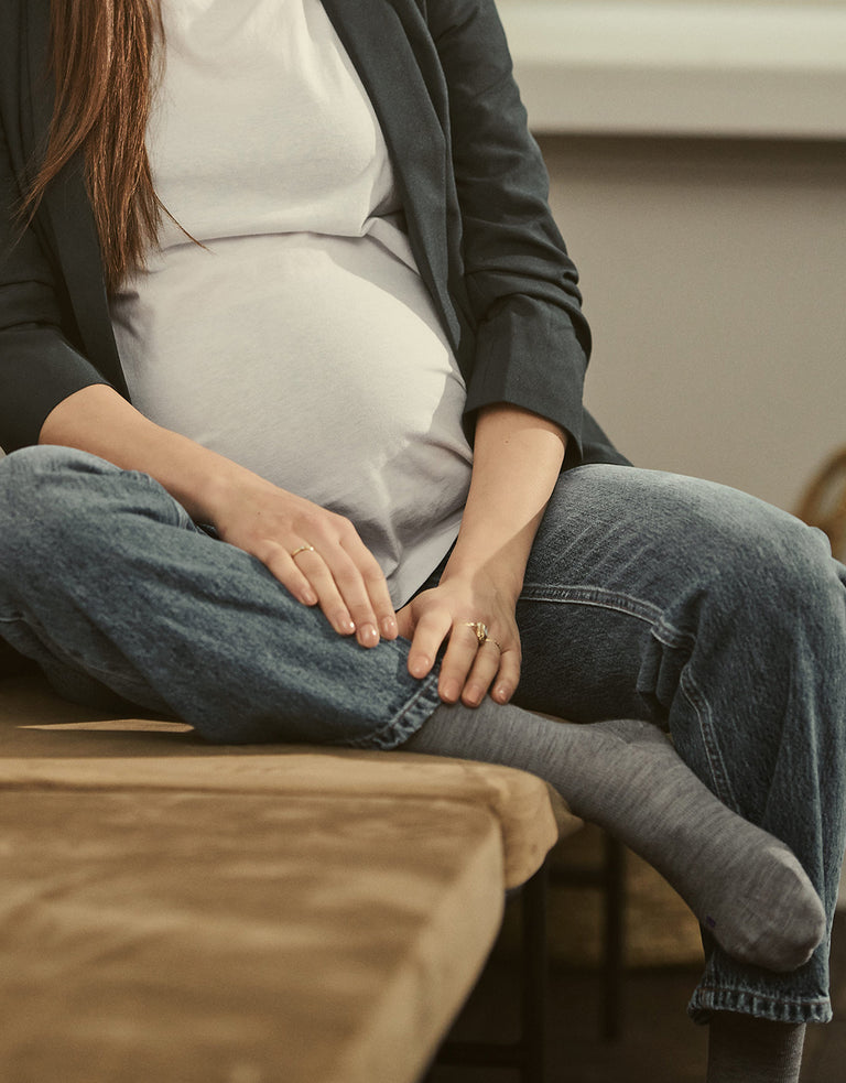 Pregnant woman sitting on a wooden bench.
