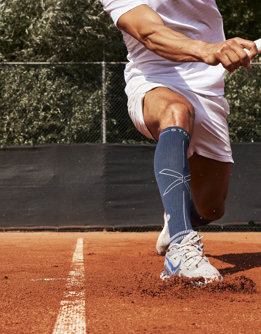 Person slides forward with his foot on a tennis court.