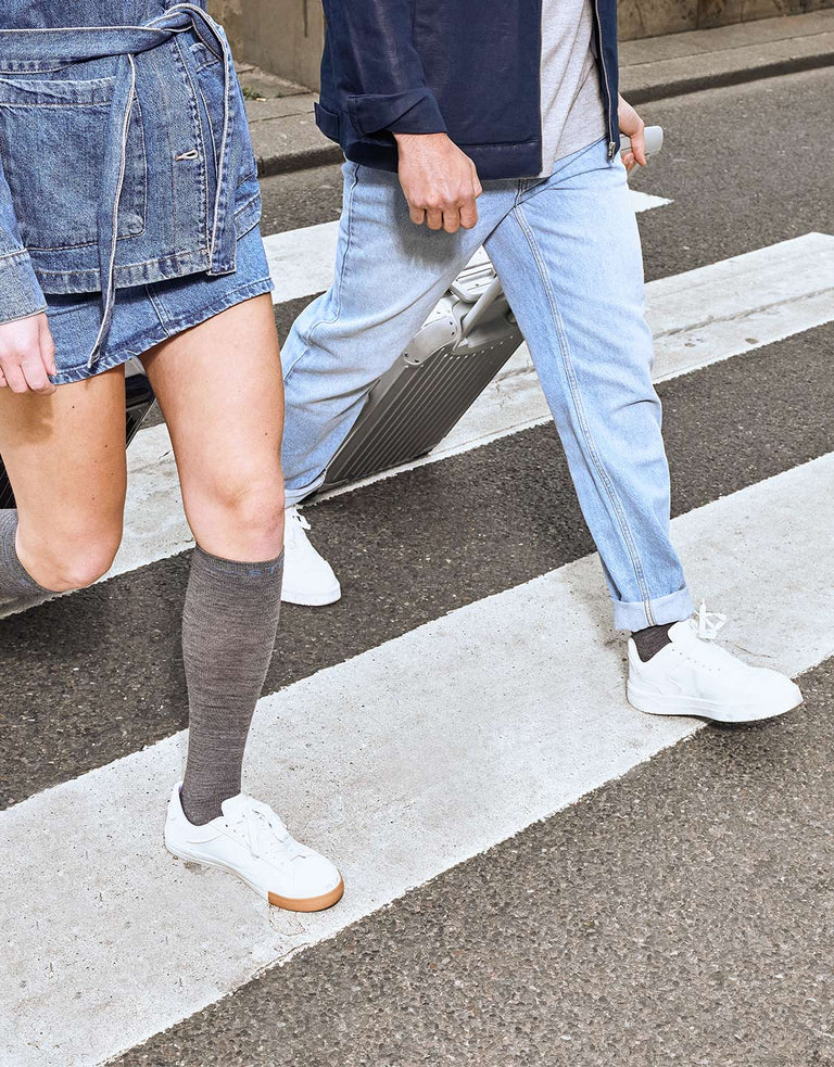 Two people waking with grey socks across a crossroad. 