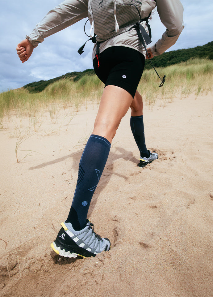  A person walks across the sand with high socks on.