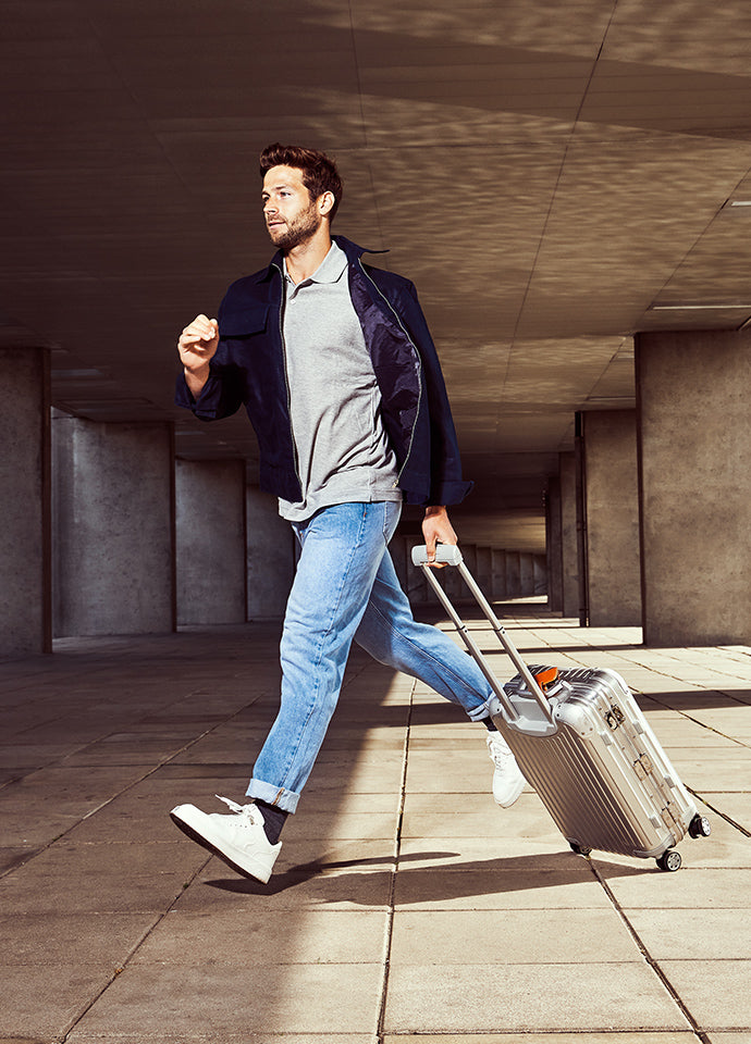 Man running over street with suitcase wearing travel compression socks in the sun.