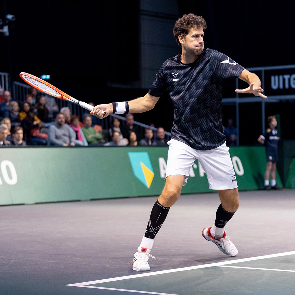 Man in full concentration playing an indoor tennis match.