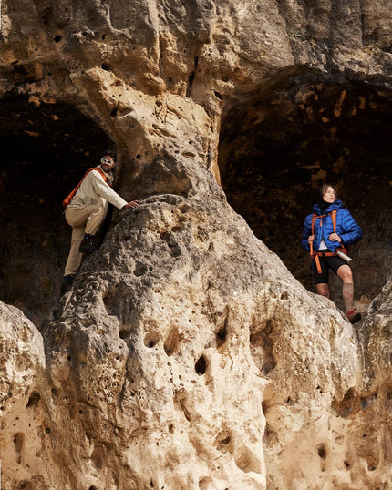 Two individuals standing on the ground wearing hiking attire.