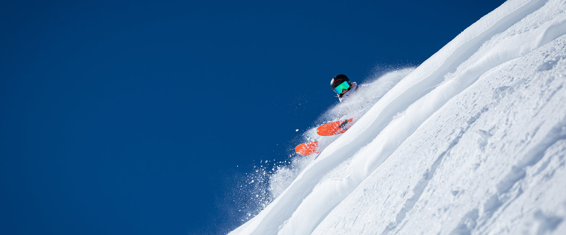 Skier in the snow with orange skis.