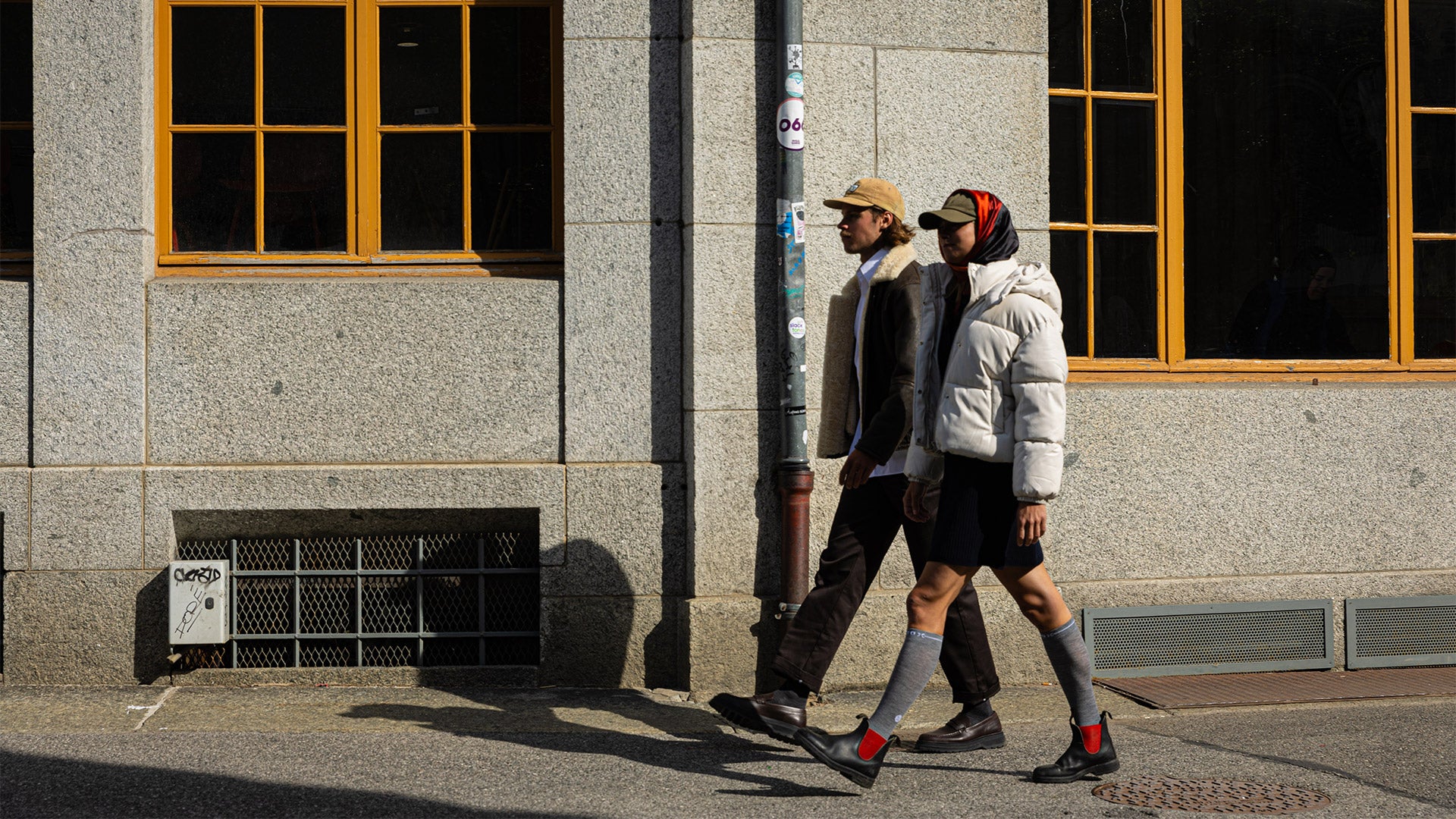 Two people walking with a building in the background.