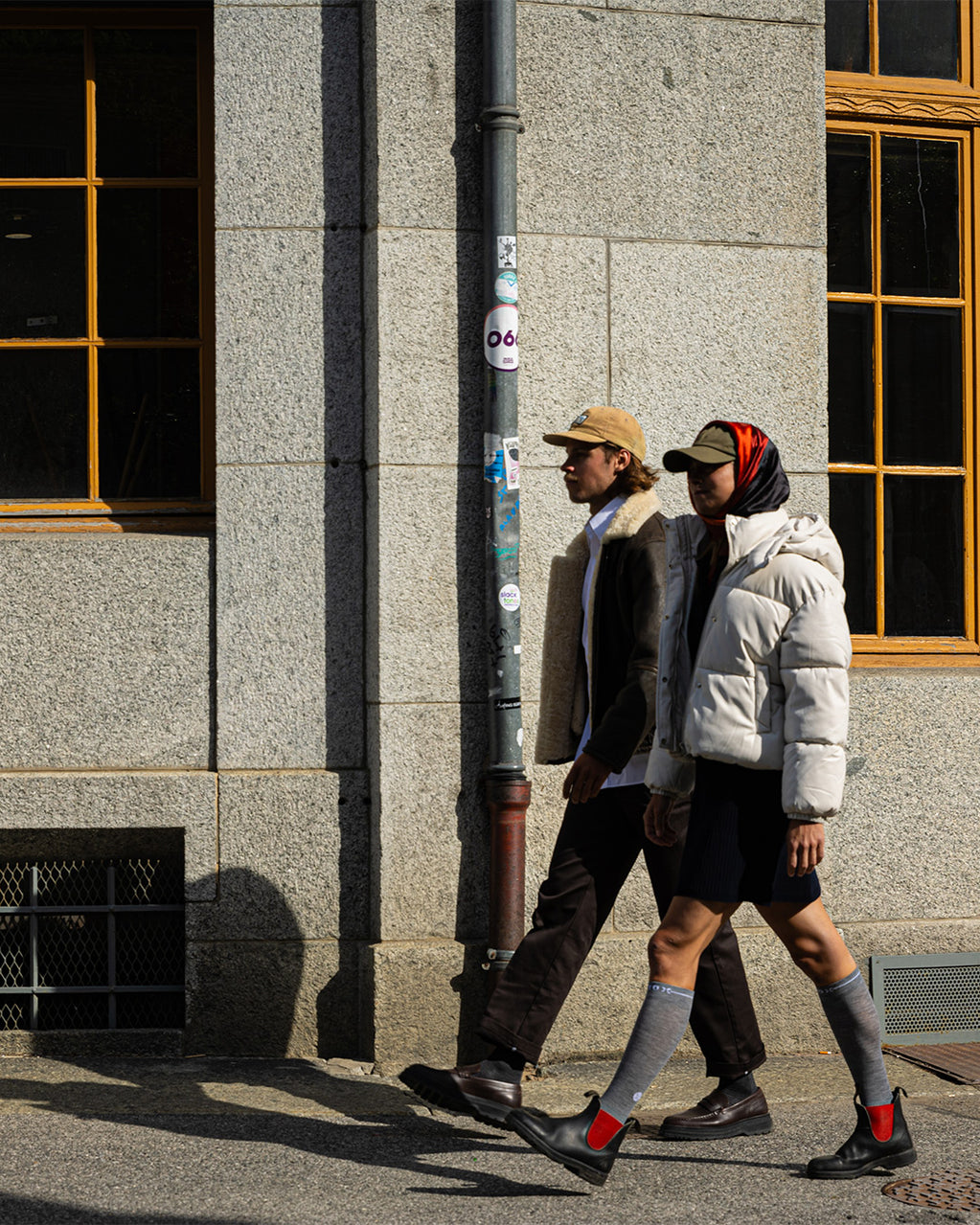 Two people walking with a building in the background.