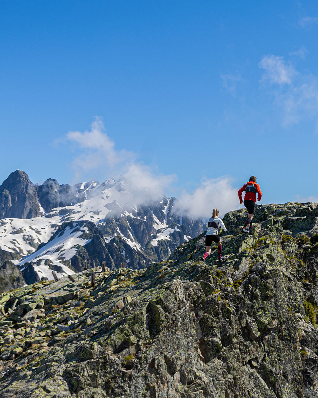 Couple running on rocks in the mountains/.