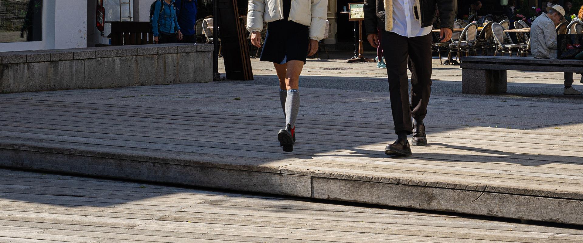 Two people are walking on a wooden floor.