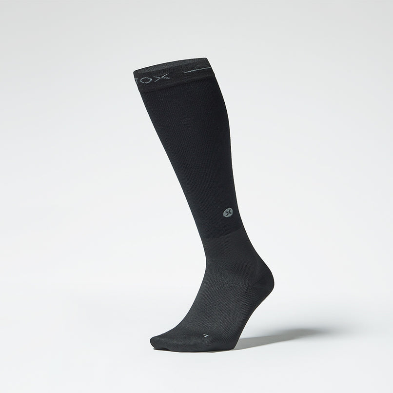 The front of a black knee high compression sock.