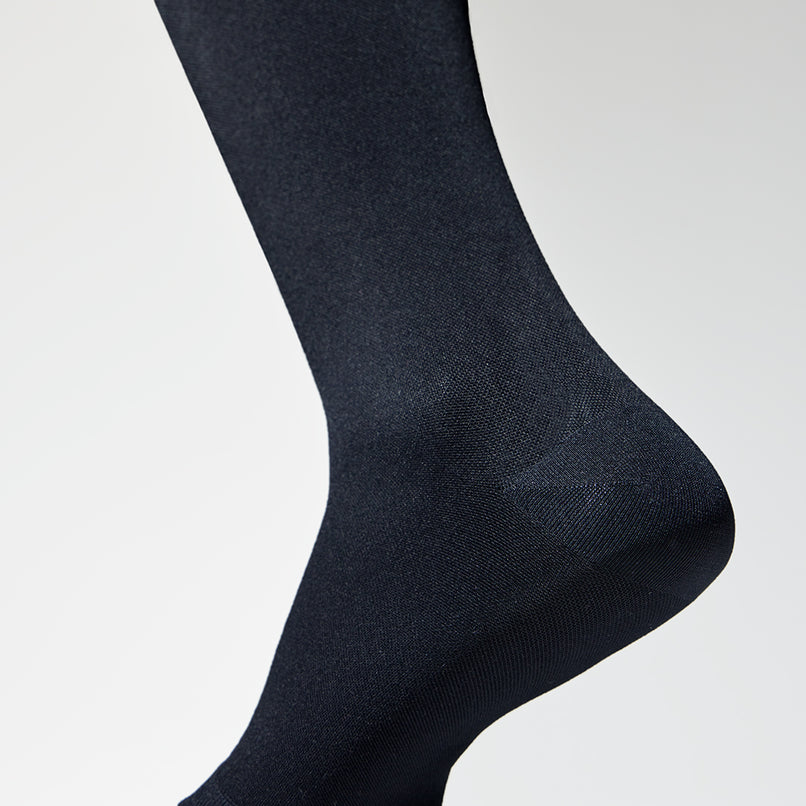 Detailed view of a medical thigh high stocking in black.