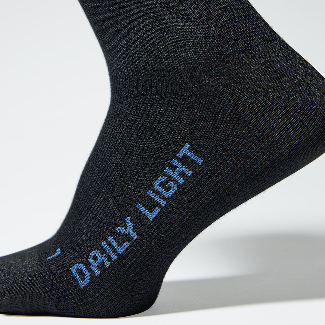 A close up of a black mid calf compression sock with blue text.