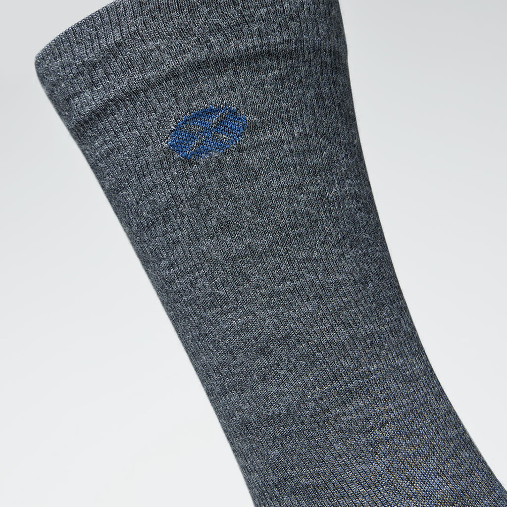 A close up of a grey mid calf compression sock with a blue logo.