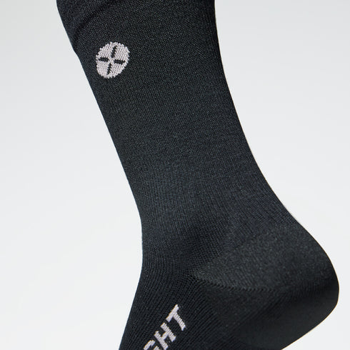 Close up of a black mid calf compression sock with a white logo.