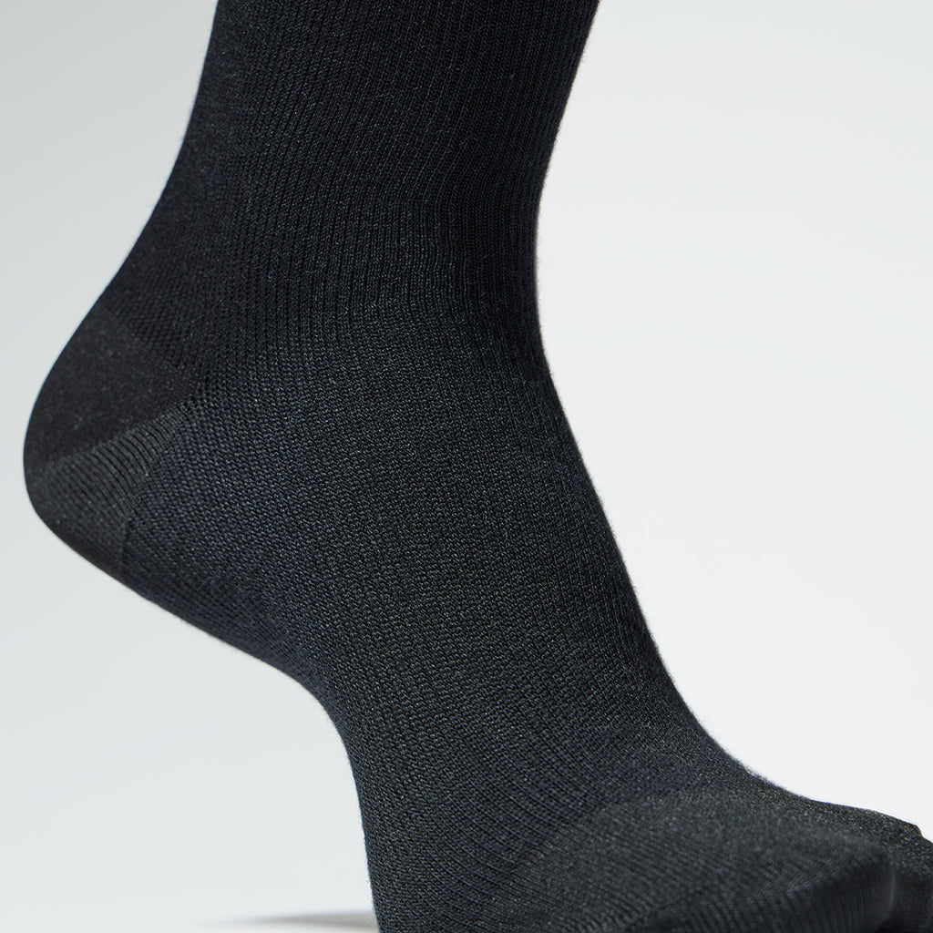 Close up of a black mid calf compression sock.