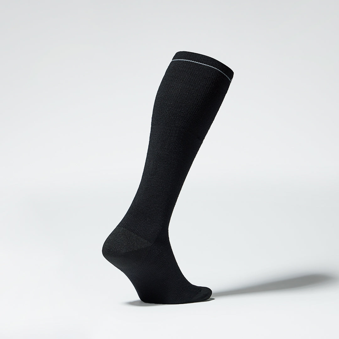 Black knee high compression sock with grey details seen from the side.