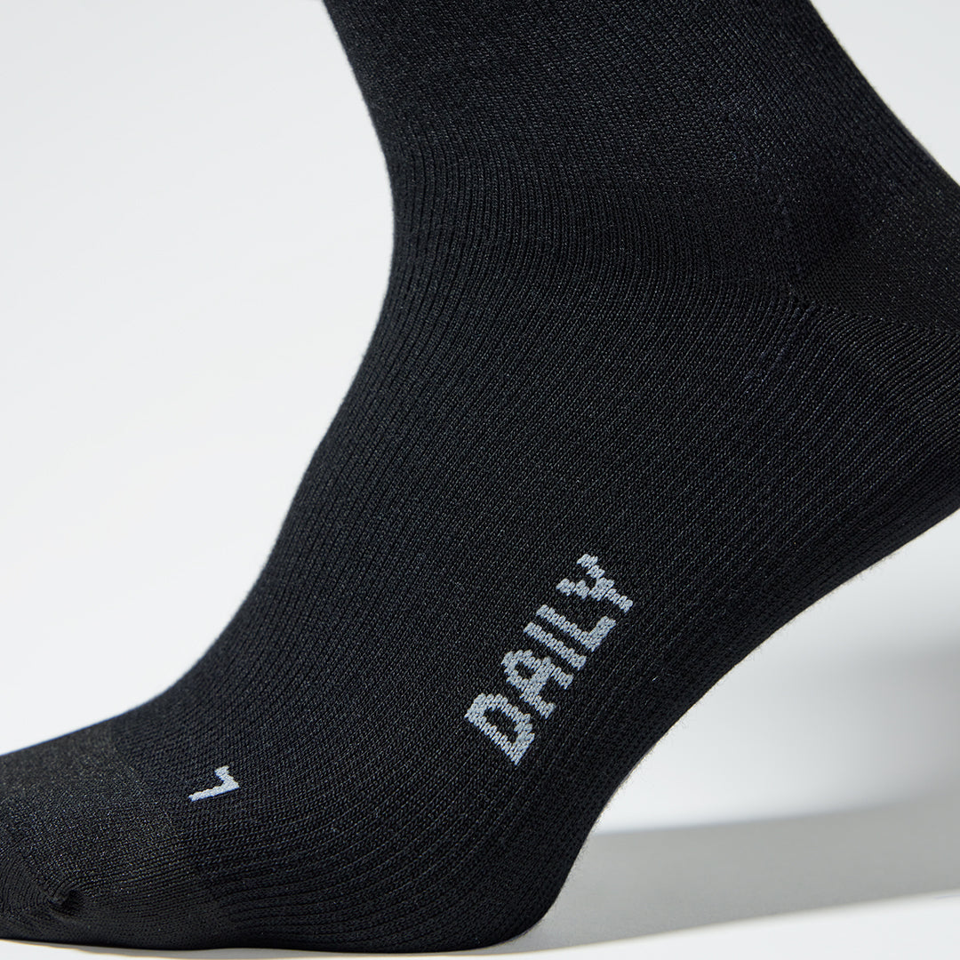 A close up of a black compression sock with grey text.