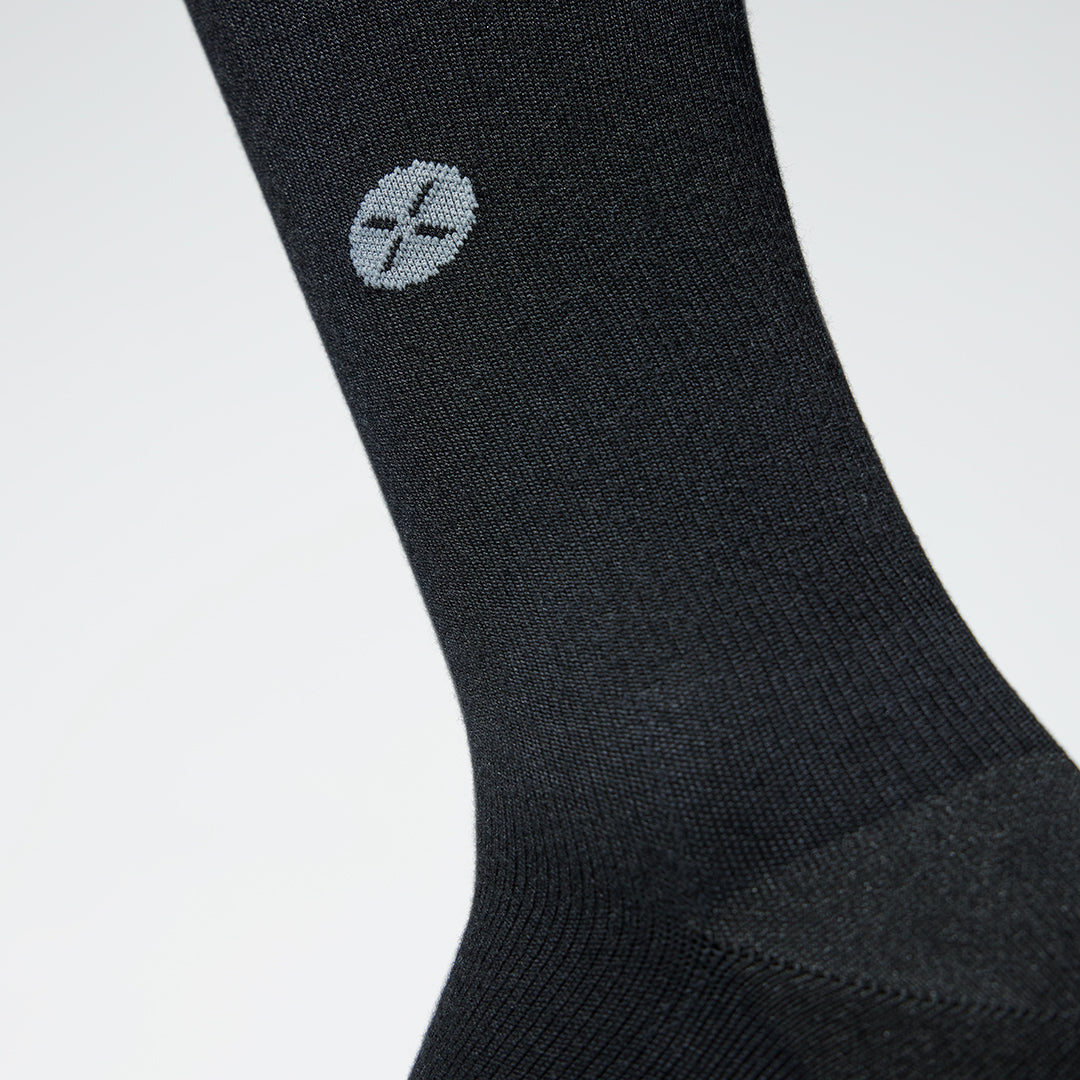 A close up of a black compression sock with a little grey logo.
