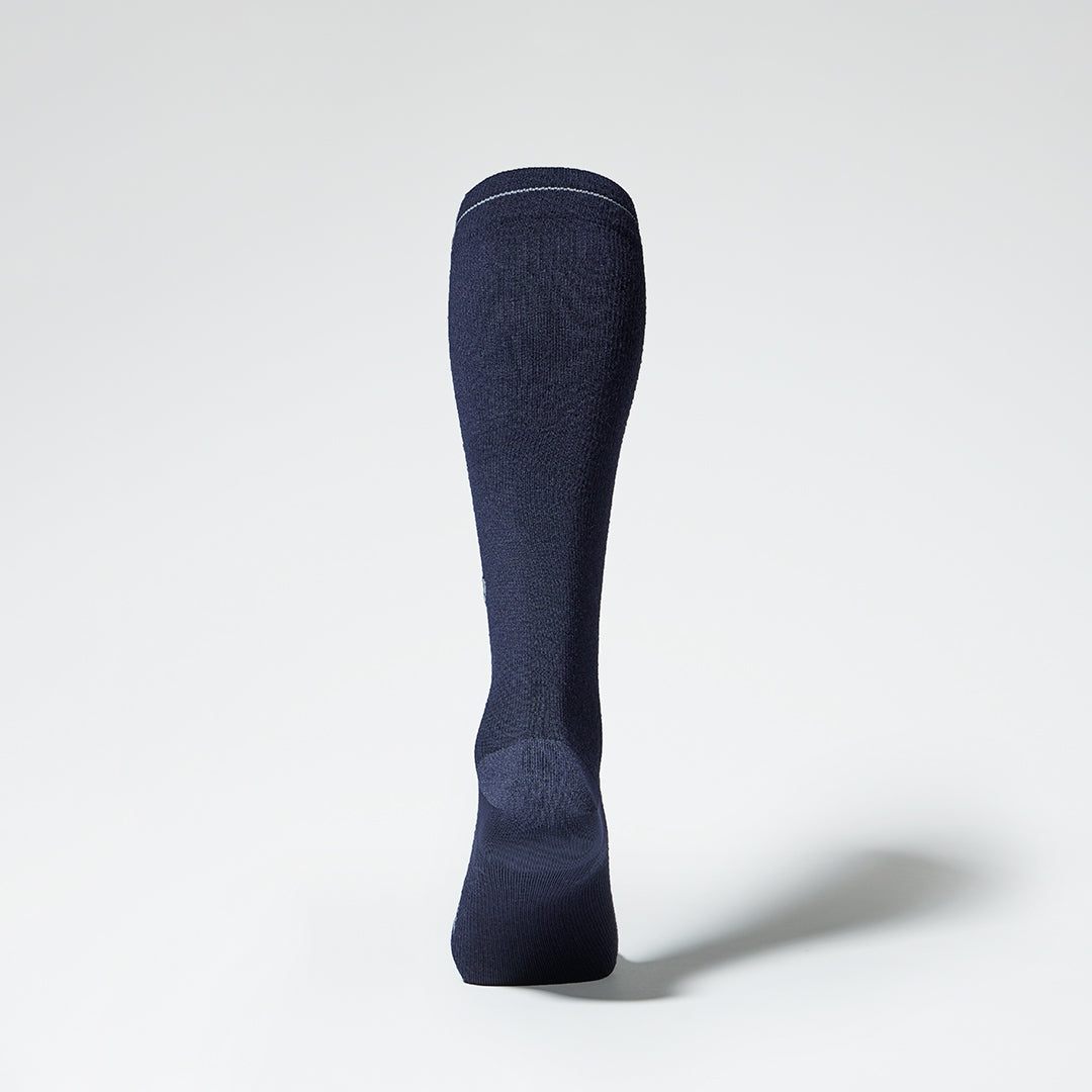 Dark blue knee high compression sock with grey details seen from the back.