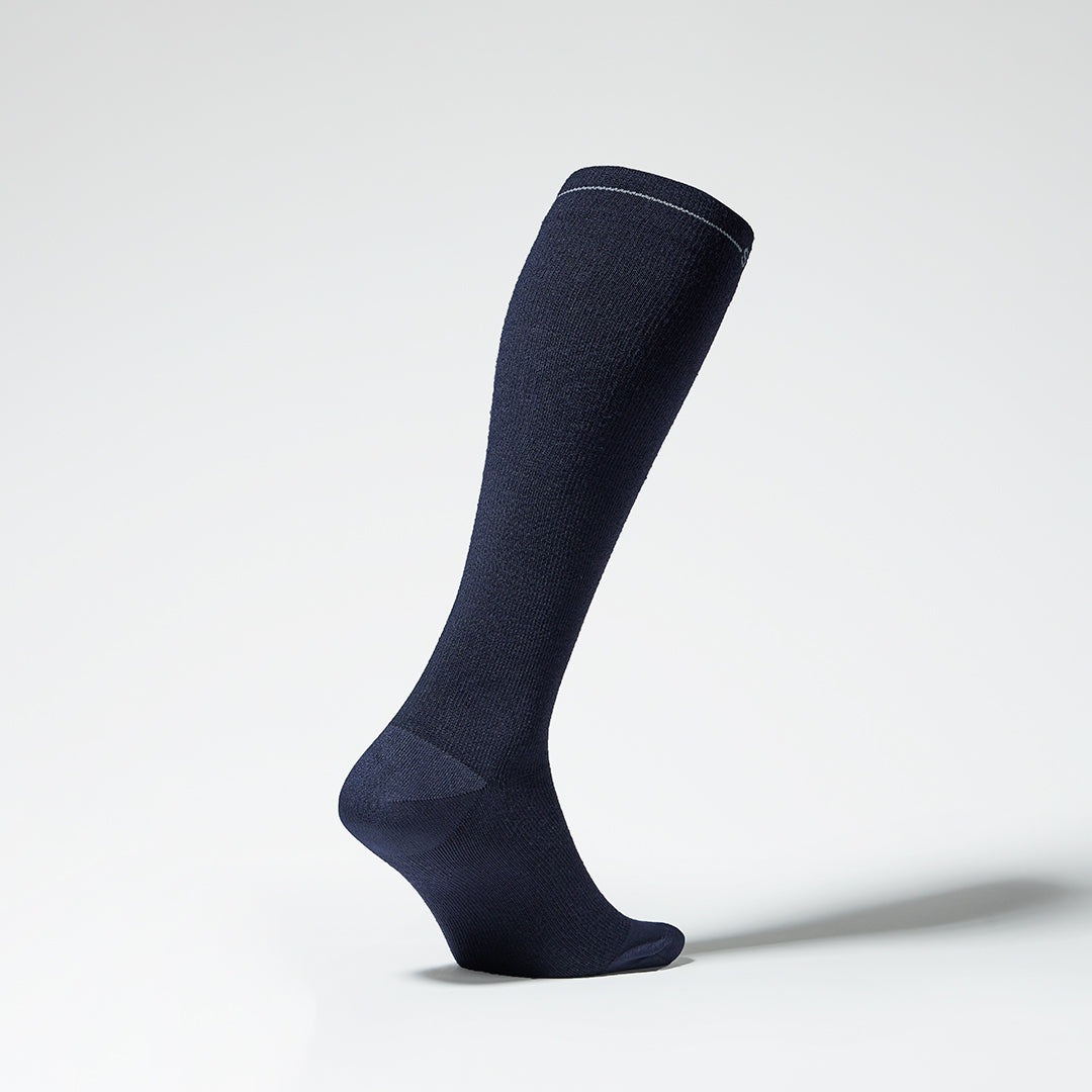 Dark blue knee high compression sock with grey details seen from the side. 