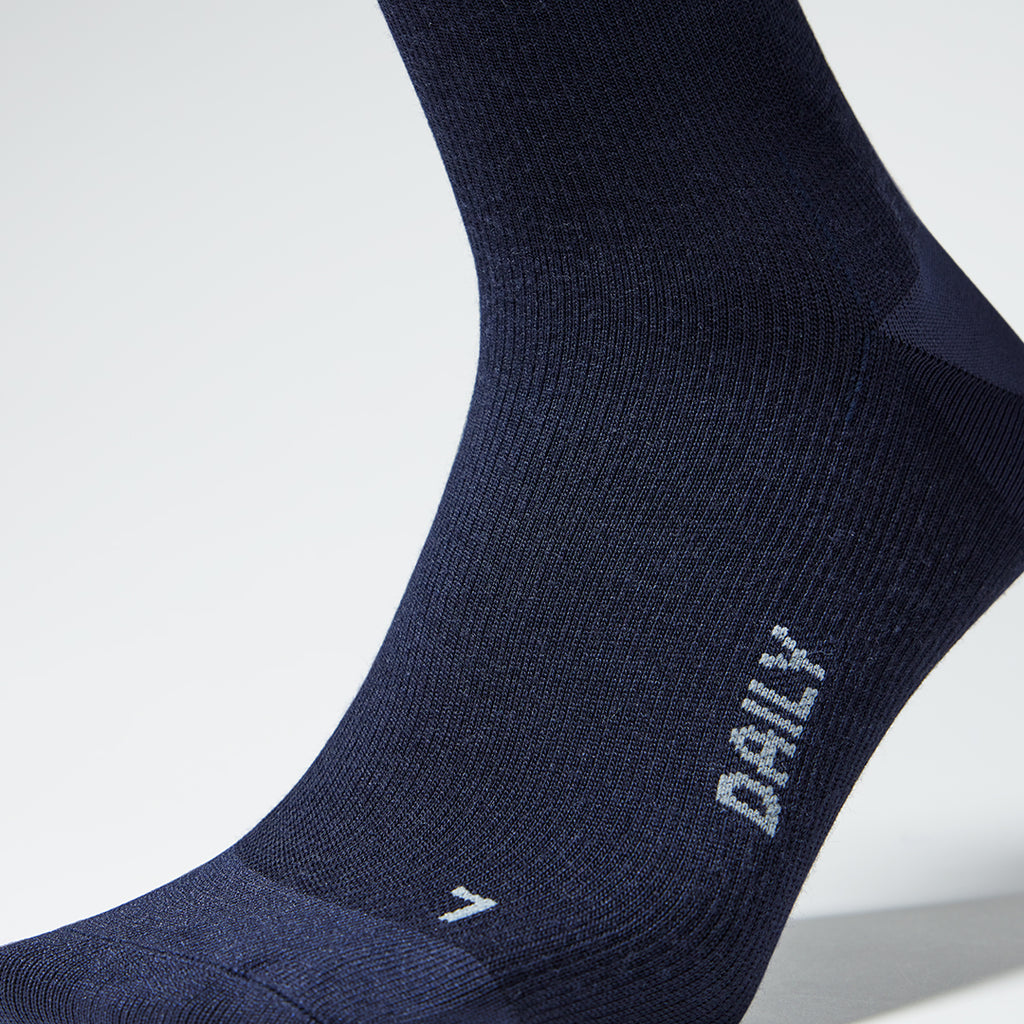 A close up of a dark blue left foot compression sock with grey text.  