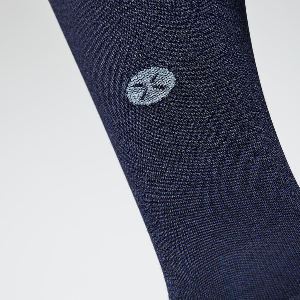 A close up of the shin of a dark blue compression sock with a grey logo.