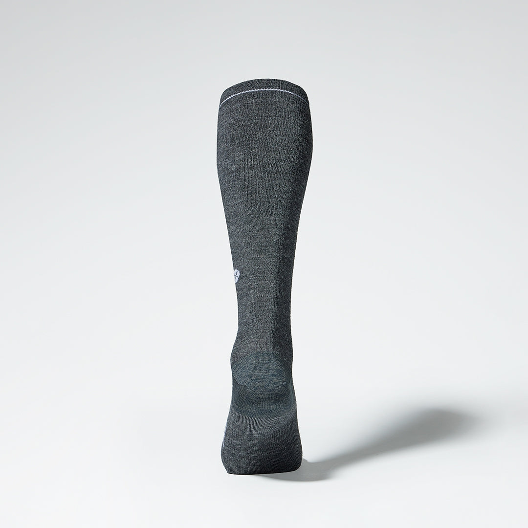 Dark grey knee high compression sock with white details seen from the back.