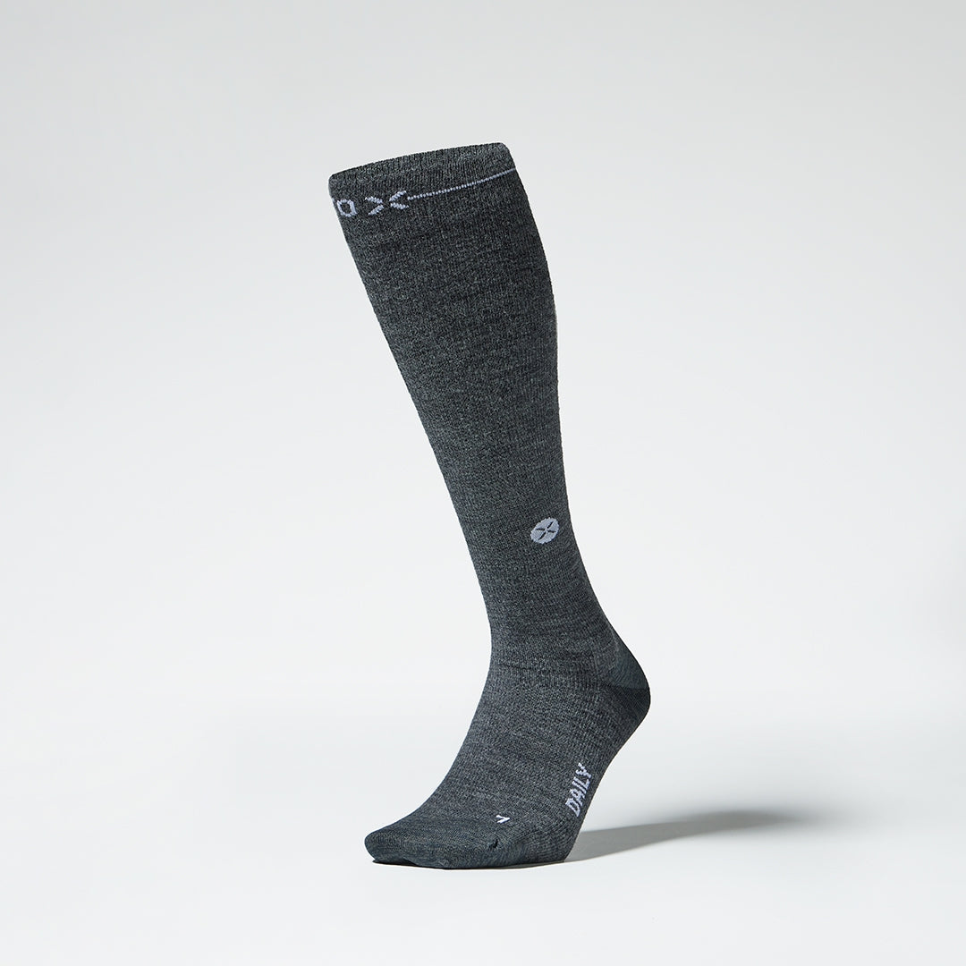 Dark grey knee high compression sock with white details seen from the front.