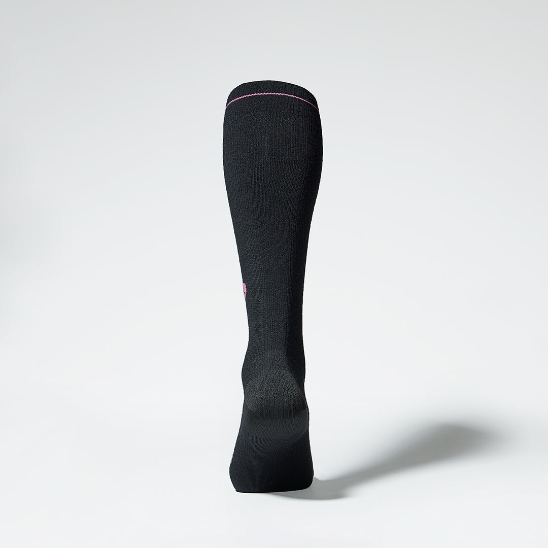 Back view of a black knee high compression sock with fuchsia details.