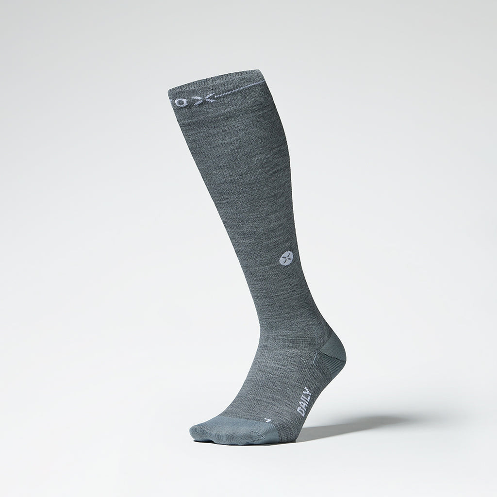 Front view of a grey knee high compression sock with white details.