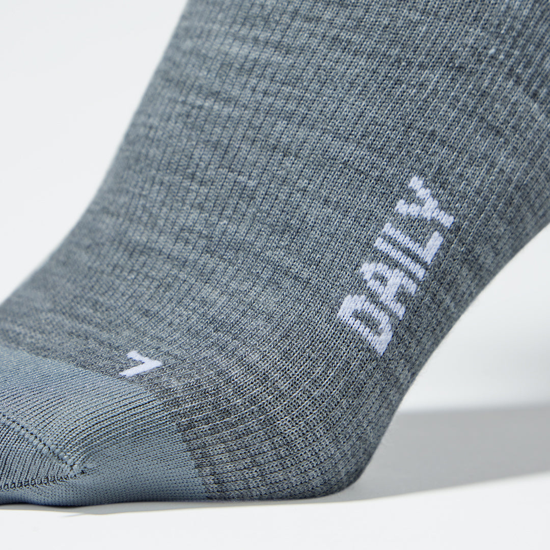 A close up of a silver grey compression sock with white text.