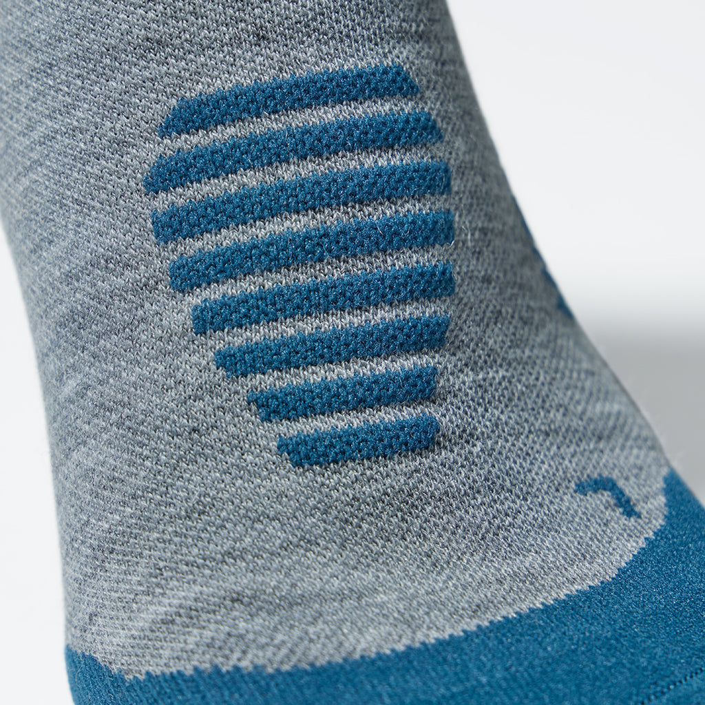 Close up of an ankle high compression sock in silver grey with teal details.