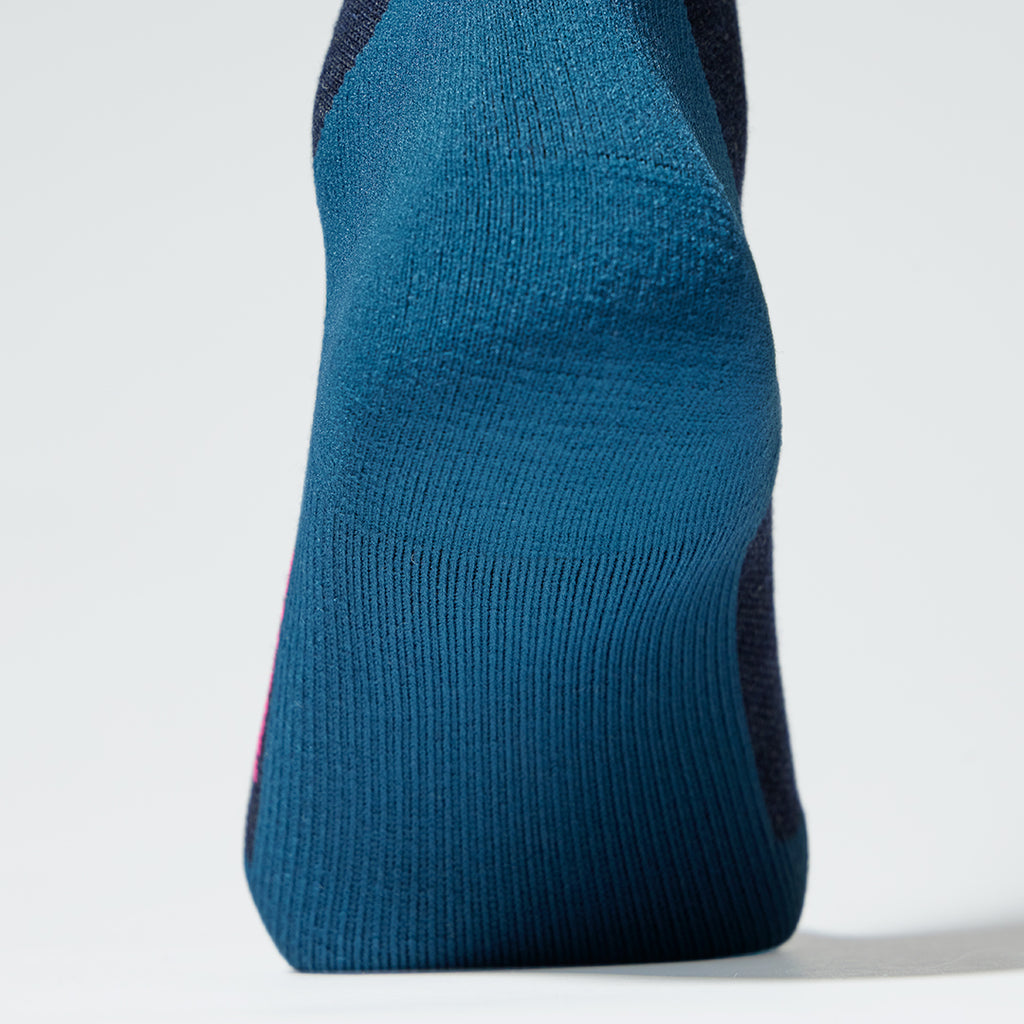 Close up of a dark blue ankle high compression sock with a blue heel.