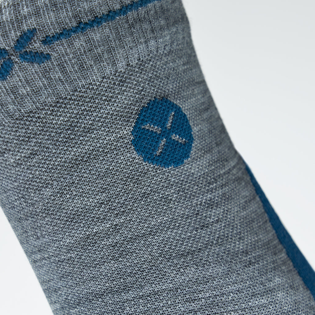 Detailed view of a grey ankle compression socks with teal details. 