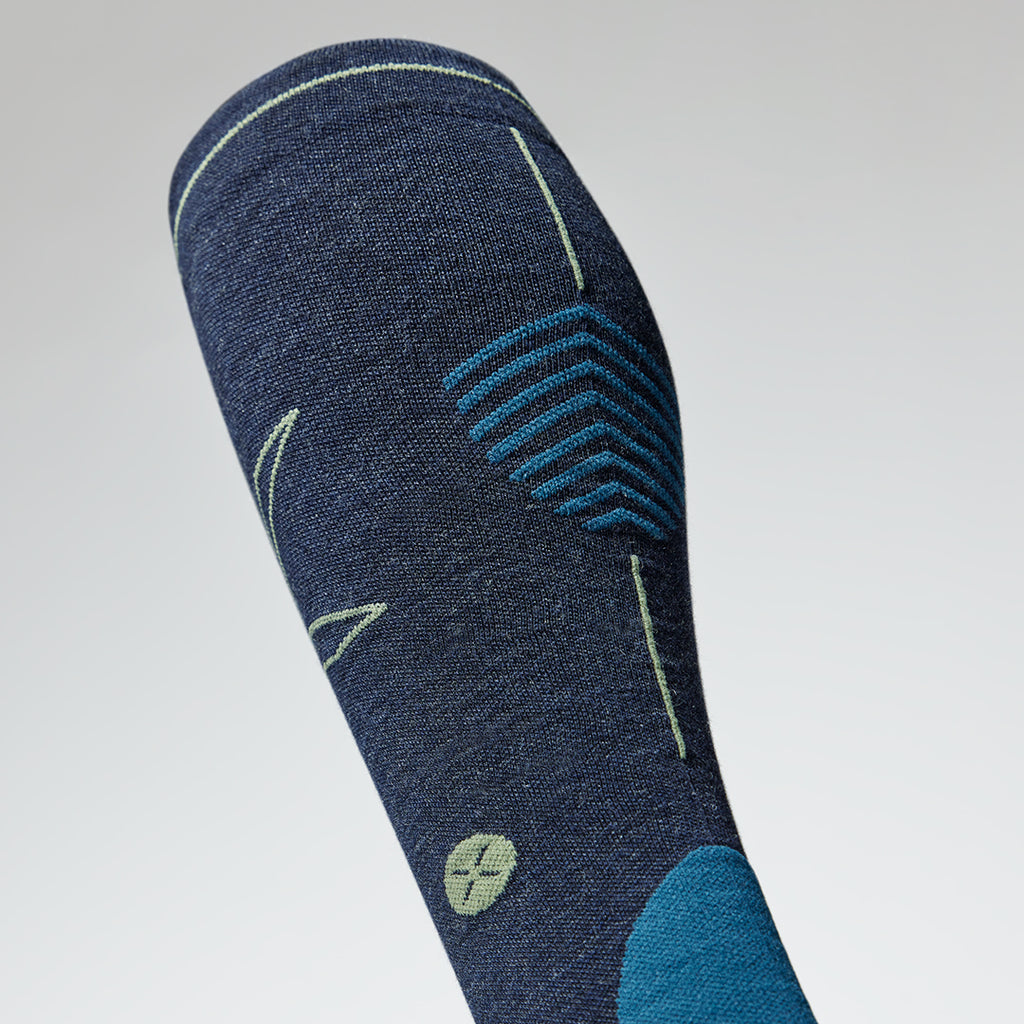 Close up of a dark blue compression sock with an olive green logo.