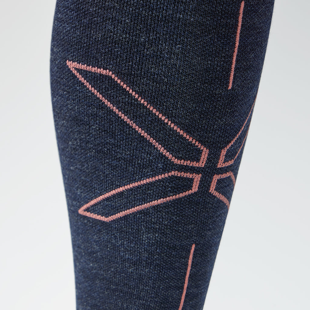 Close up of a dark blue compression sock with a coral coloured logo.