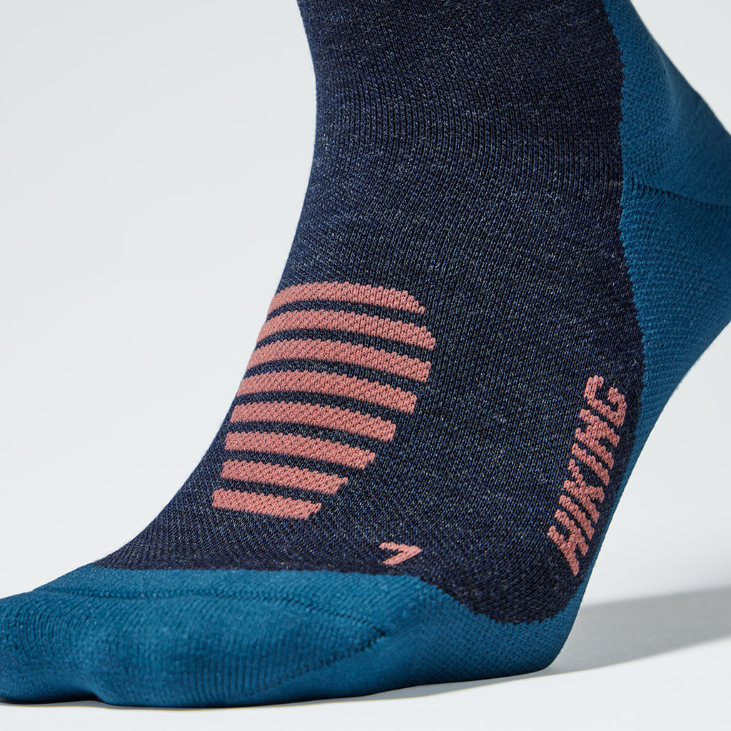 Close up of a dark blue compression sock with coral coloured text.