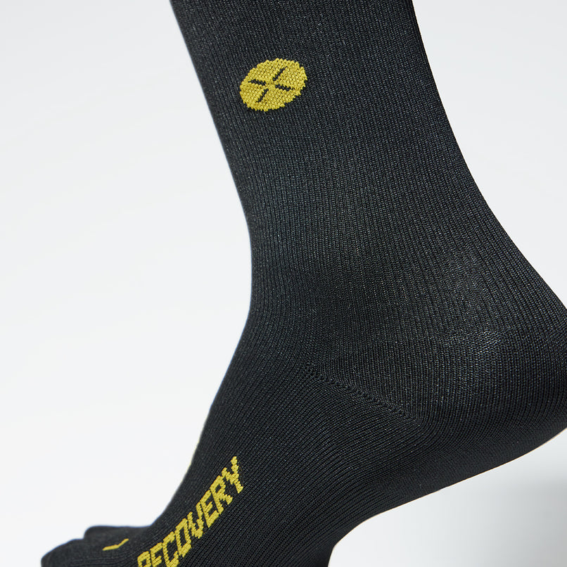 Detailed view of a black compression sock with yellow details.