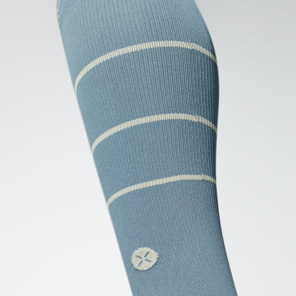 Close up of a knee high compression sock in grey with beige lines. 