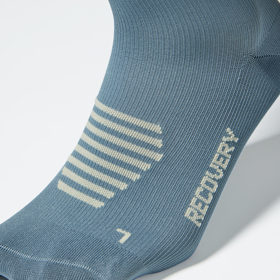Close up of a compression sock in grey with beige accents. 