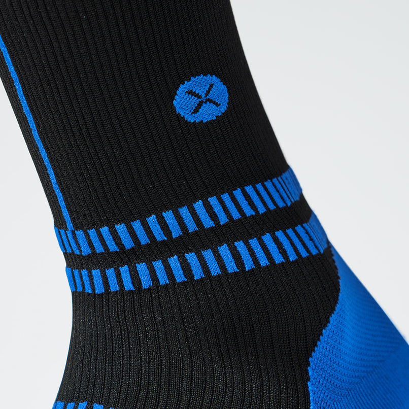 Close up of a black compression sock with a blue logo.
