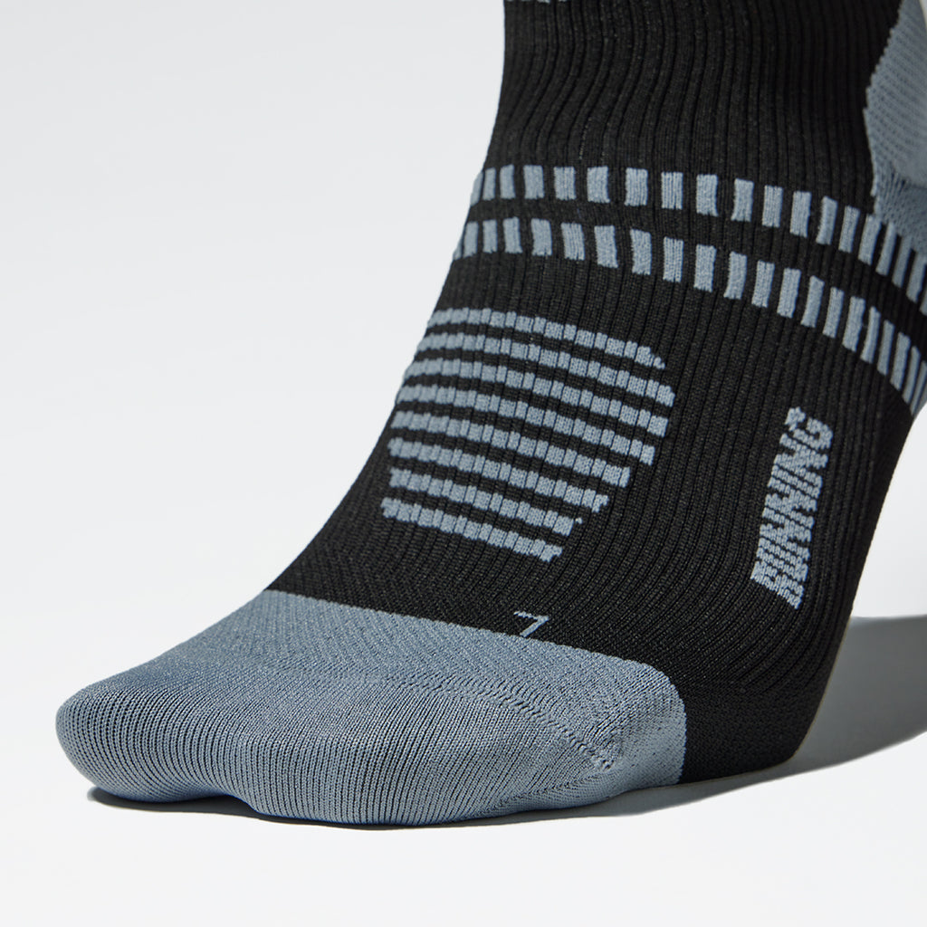 Close-up of a left foot black sock with grey stripes.