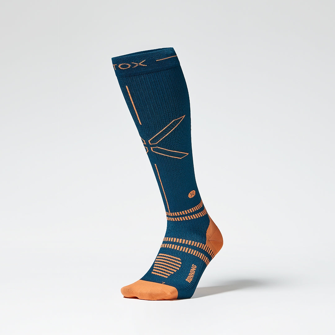 A knee high compression sock with orange details from the front.
