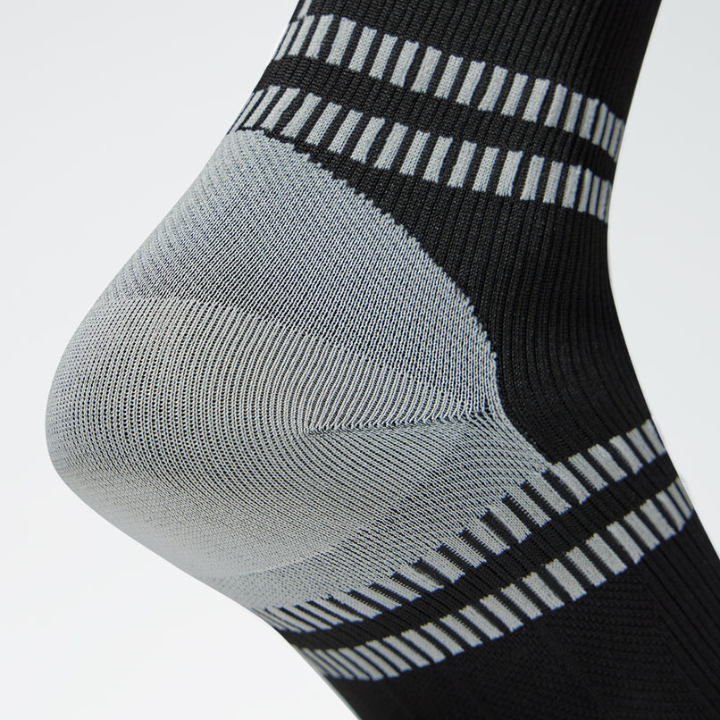 Close up of a black colored compression sock with grey accents. 