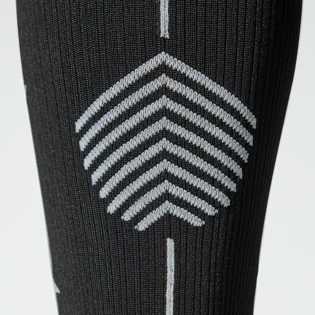 Close up of a black colored compression sock with a grey logo. 