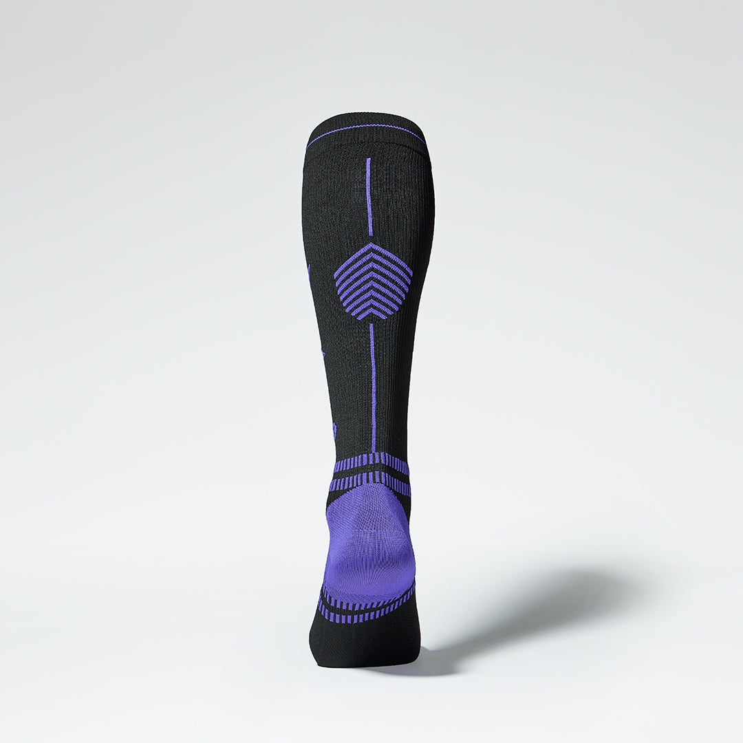 View of the back of a knee high compression sock in black with pink details.