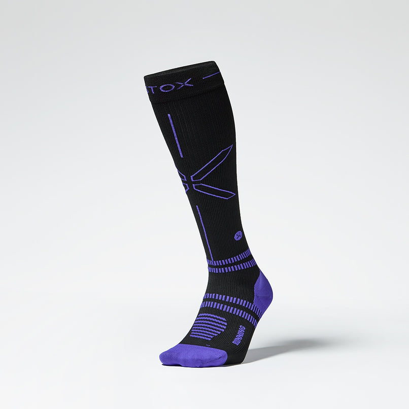 Front view of a black colored knee high compression sock with purple accents. 