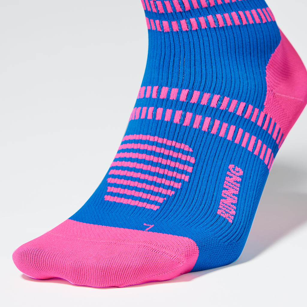 Close up of a blue colored compression sock with a pink logo. 