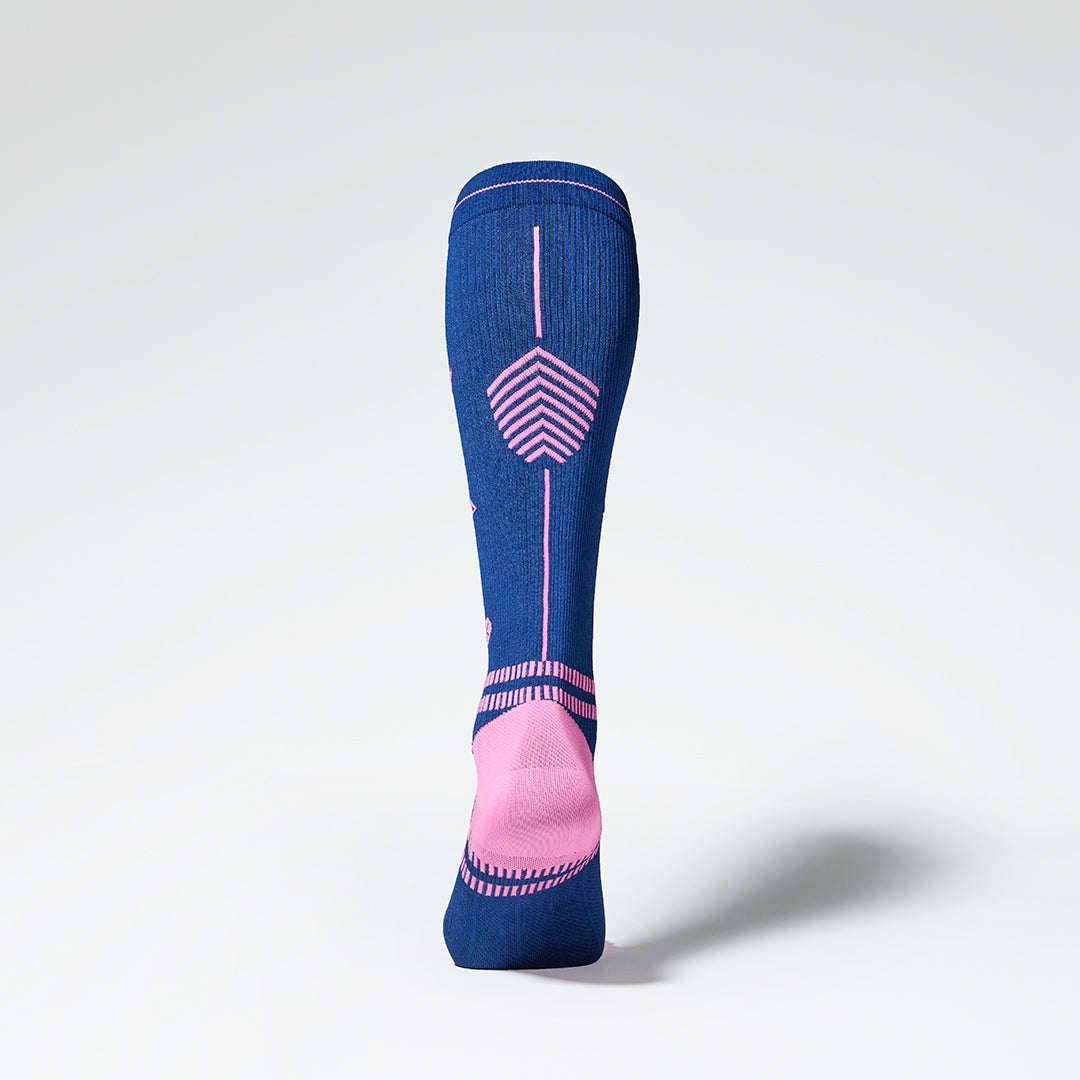 View of the back of a knee high compression sock in dark blue with pink details. 