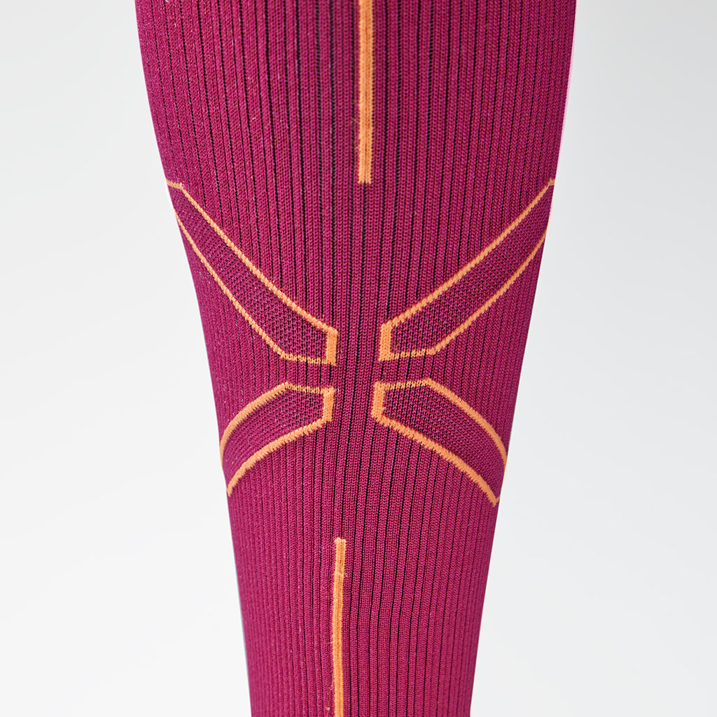 Close up of a fuchsia compression sock with an orange logo. 