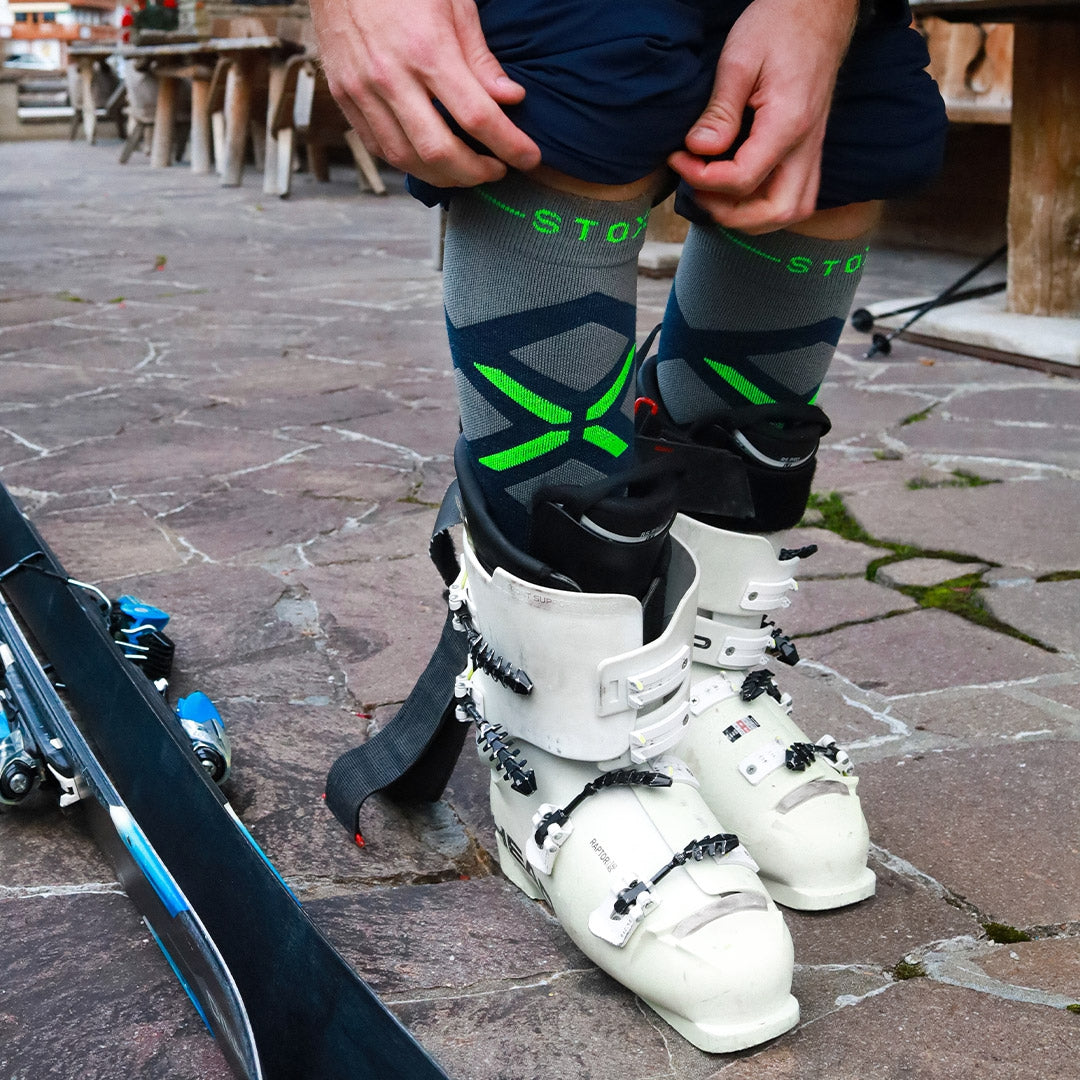 Man wearing knee high socks with green details while skiing boots. 